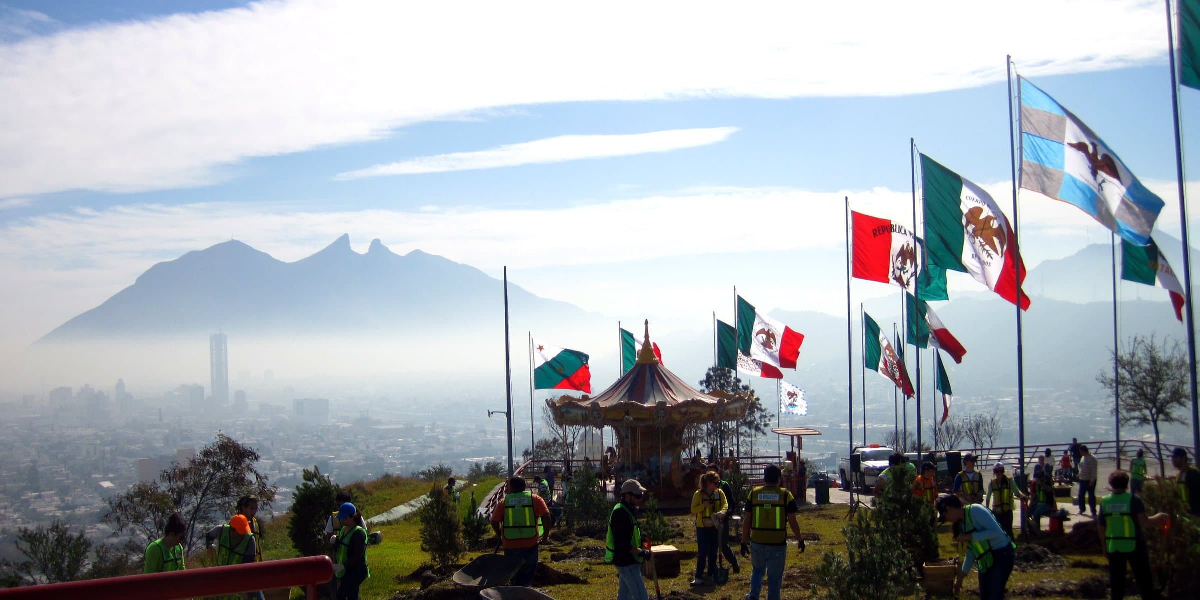 Jornada de instalación de pinos en un parque con el Cerro de la Silla al fondo